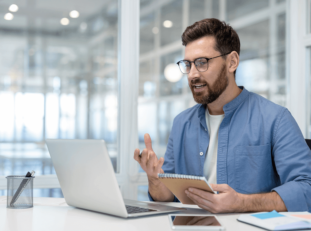 Man holding notebook speaking in online meeting