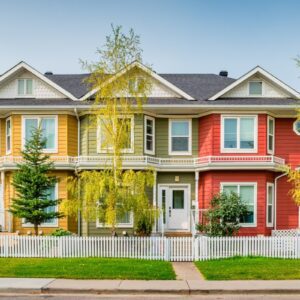 Row of colorful townhouses behind white picket fence