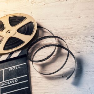 Film reel and clapperboard on wooden surface.