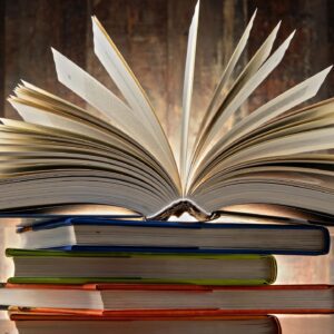 Open book on top of stacked books.