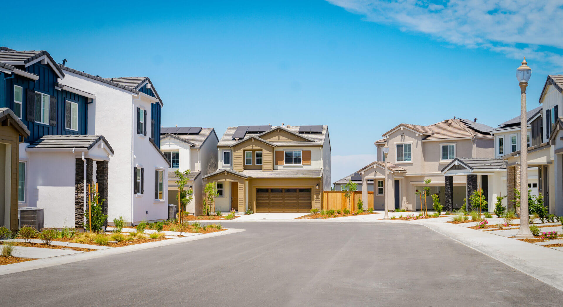 Newly built suburban homes under a clear blue sky.