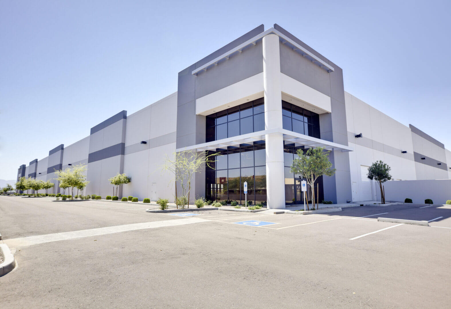 Modern commercial building with large glass entrance and clear sky.
