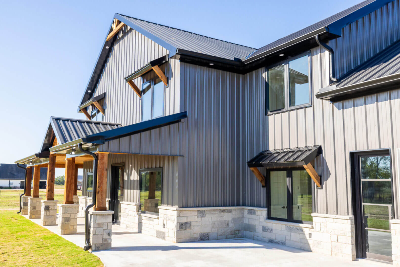 Modern two-story house with metal siding and large windows.