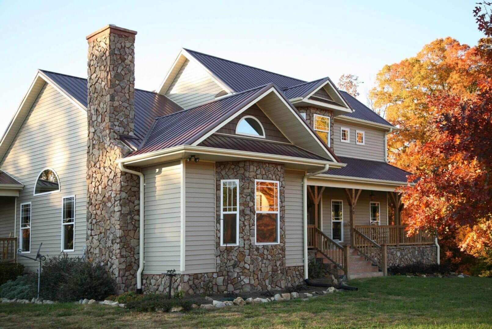 A charming two-story house with stone chimney and vinyl siding.